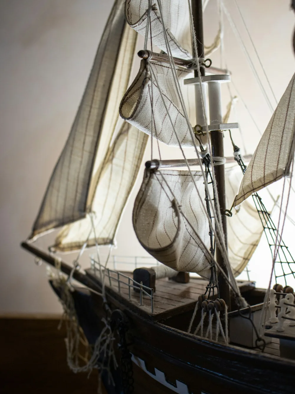 Modelo de velero de madera con cubierta, jarcia y velas de tela vistas de cerca